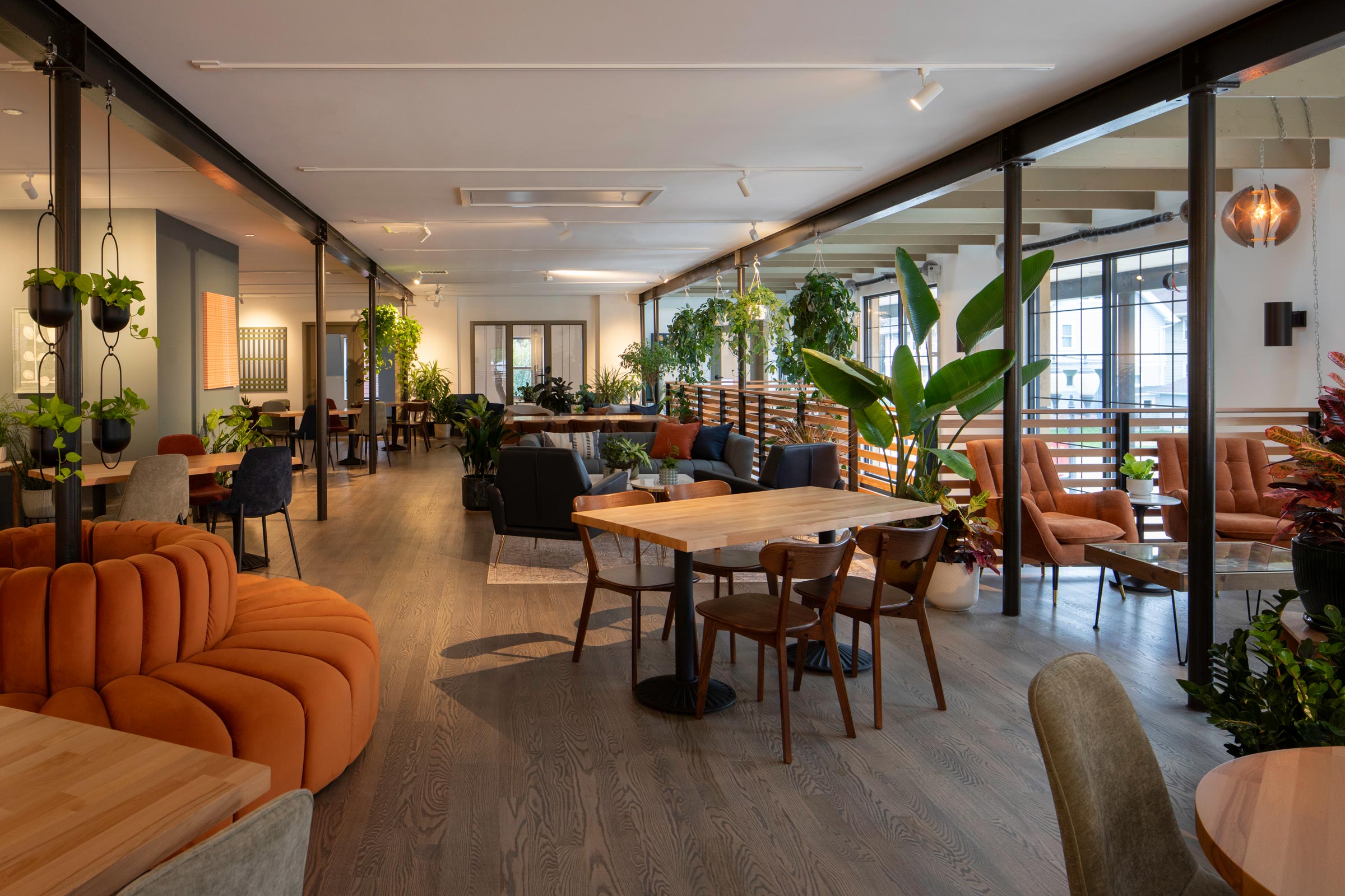 Second-floor lounge with soft seating, plants, and natural light.